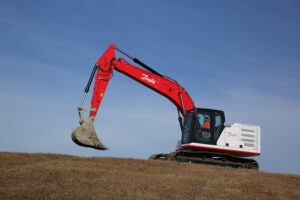 A Danfoss excavator on a dirt hill.