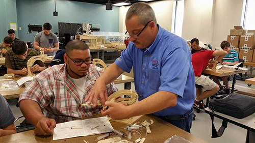 Bob Hammond (Deltrol Fluid Products) works with a student from Leyden High School to build a hydraulic robotic arm during the SCC event held at Triton College.