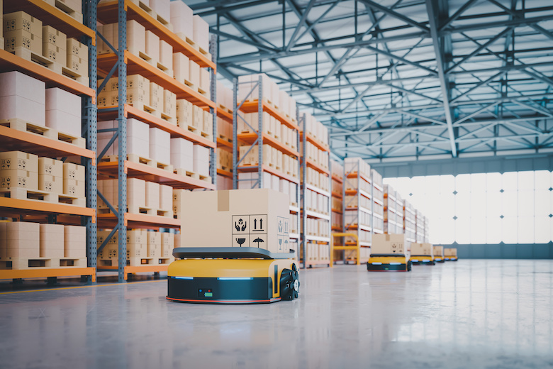 An automated guided vehicle carrying a box in a warehouse.